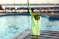 Glass of fresh summer cocktail on table near swimming pool outdoors. Space for text Royalty Free Stock Photo