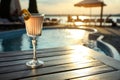 Glass of fresh summer cocktail on wooden table near swimming pool outdoors at sunset Royalty Free Stock Photo