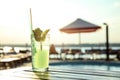 Glass of fresh summer cocktail on wooden table near swimming pool outdoors at sunset Royalty Free Stock Photo