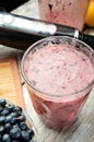 glass with fresh vegetarian banana - berries cocktail served on wooden rural table with fresh banana, berries and blender .