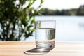 Glass of fresh water on light grey table outdoors, closeup