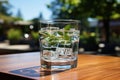 Glass of fresh water on light grey table outdoors, closeup