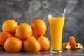 Glass of freshly squeezed orange juice standing on grey background with a fresh oranges Royalty Free Stock Photo