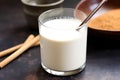 glass of frothy horchata with a spoon in the background