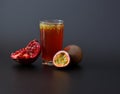 A glass of fruit juice with seeds on a black background, next to a ripe passion fruit and a pomegranate fruit with seeds Royalty Free Stock Photo