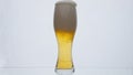 Glass full foamy beer overflowing in super slow motion close up. Bubbling foam. Royalty Free Stock Photo
