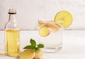 Glass with ginger water and bottle of ginger oil on white table on light background. Royalty Free Stock Photo