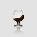 Glass glass with an alcoholic drink or cognac and splashes on a light background. Isolated, splash Royalty Free Stock Photo