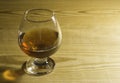 Glass glass with cognac on a wooden table. Free space for text on the side. Royalty Free Stock Photo