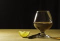 A glass glass of cognac on a wooden table, a slice of lemon and a cigar Free space for text on the side Royalty Free Stock Photo