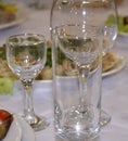 Crockery. Glass glasses, wine glasses, glasses, plates standing on a white tablecloth and reflecting light glare. Royalty Free Stock Photo