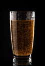 Glass with golden liquid in bubbles on a black background. Effervescent pills vitamin C with orange flavor.