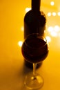 A glass of good red wine, a close-up, a bottle and a bokeh of lights. Royalty Free Stock Photo