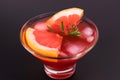 A glass of grapefruit cocktail with ice on a black background. Close-up. Royalty Free Stock Photo