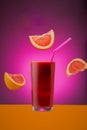 Glass of grapefruit juice isolated on a pink background.