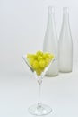 Glass with grapes on the background of a blurry empty wine bottles.