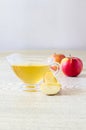 Glass gravy boat with apple cider vinegar and fresh fruits on a light wooden table. Close-up. Royalty Free Stock Photo