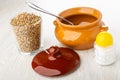 Glass of buckwheat, spoon in ceramic pot, cap, salt shaker on table