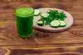 Glass of green detox smoothie of cucumber and parsley on wooden table