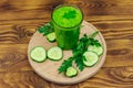 Glass of green detox smoothie of cucumber and parsley on wooden table