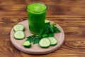 Glass of green detox smoothie of cucumber and parsley on wooden table