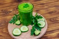 Glass of green detox smoothie of cucumber and parsley on wooden table