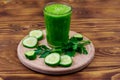 Glass of green detox smoothie of cucumber and parsley on wooden table