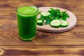 Glass of green detox smoothie of cucumber and parsley on wooden table