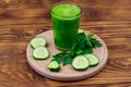 Glass of green detox smoothie of cucumber and parsley on wooden table