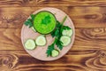 Glass of green detox smoothie of cucumber and parsley on wooden table. Top view