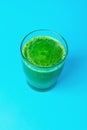 Glass with Green Fresh Raw Smoothie from Leafy Greens Vegetables Fruits Spinach Apples Bananas Kiwi Zucchini on Blue Background Royalty Free Stock Photo