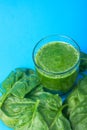 Glass with Green Fresh Smoothie from Leafy Greens Vegetables Fruits Bananas Kiwi Cucumber Apple. Scattered Spinach Leaves on Blue Royalty Free Stock Photo