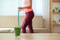 Glass of green smoothie with blurred woman trying to lose weight on background