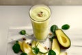 A glass of green juice with a slice of avocado and spinach on a white table Royalty Free Stock Photo