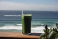 glass of green juice, with view of the ocean, for a health boost on vacation