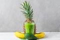 Glass of green smoothie made of spinach, pineapple, banana and avocado with fresh fruits and chia seeds on gray Royalty Free Stock Photo
