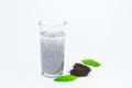 Glass of hairy basil seeds with water and dried seeds on floor with green leaves