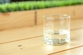 A glass with half water in it, on the wood table and green grass background Royalty Free Stock Photo