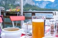 A glass of Hallstatt local beer on the table at a romantic restaurant beside the Hallstattersee Lake in High Alps Mountains, a Royalty Free Stock Photo