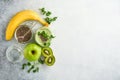 Glass of healthy green smoothie and ingredients for smoothie, fresh spinach, pea microgreens, banana, kiwi, apple and chia seed Royalty Free Stock Photo