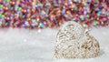 Glass heart on a snow and toned blurred color background of glittering bokeh with glowing lights. Christmas decoration. Copy space Royalty Free Stock Photo