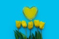 Glass heart and yellow tulips on a turquoise background, fragile love background, valentines day concept Royalty Free Stock Photo