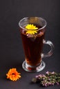 Glass of herbal tea with calendula and hyssop on a black background. Side view, close up Royalty Free Stock Photo