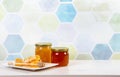 Glass honey jars with different color honey inside, lot of copy space on blue.