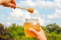 Glass honey pot in hands.