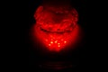 A glass hookah flask filled with bubbling water and smoke glows in the dark in red. luminescence in darkness Royalty Free Stock Photo