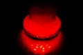 A glass hookah flask filled with bubbling water and smoke glows in the dark in red. luminescence in darkness