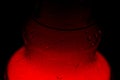 A glass hookah flask filled with bubbling water and smoke glows in the dark in red. luminescence in darkness