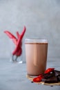 Glass of hot chocolate, cacao drink with chili pepper. On a gray background