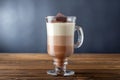 Glass of hot chocolate of three layered drink on wooden table.